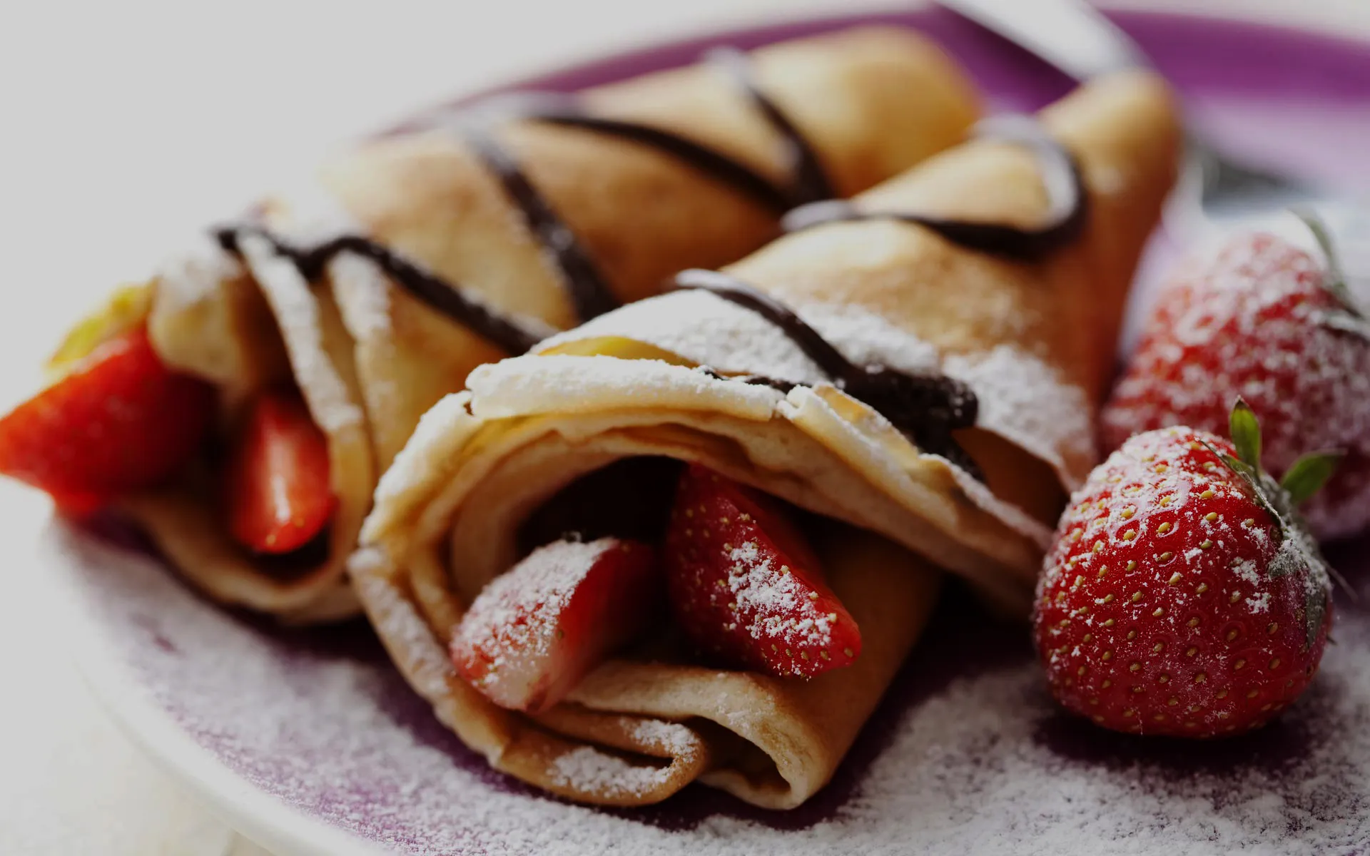 Frisch zubereitete Crêpes mit Erdbeeren und Schokosauce